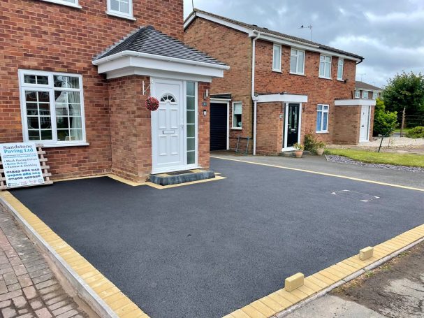 Tarmac Newly paved driveway with brick edging in front of residential houses.